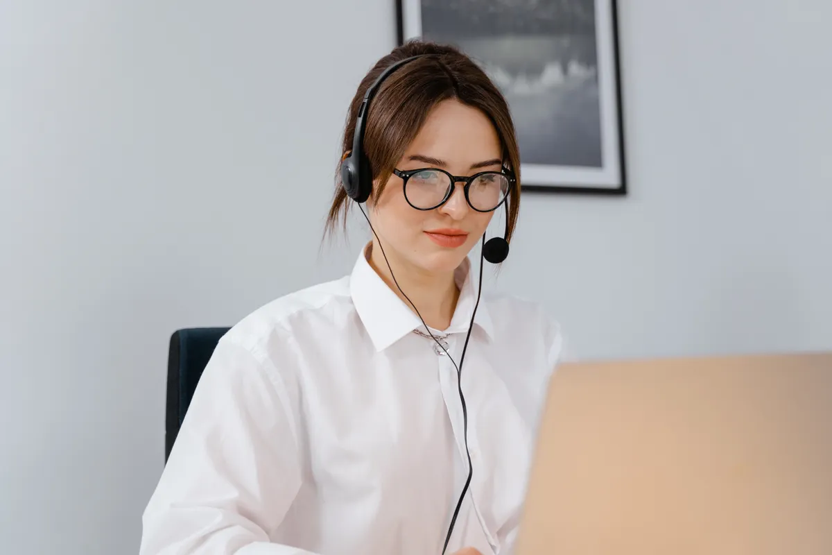 موظفة دعم تستخدم سماعة رأس أثناء العمل على حاسوب محمول.